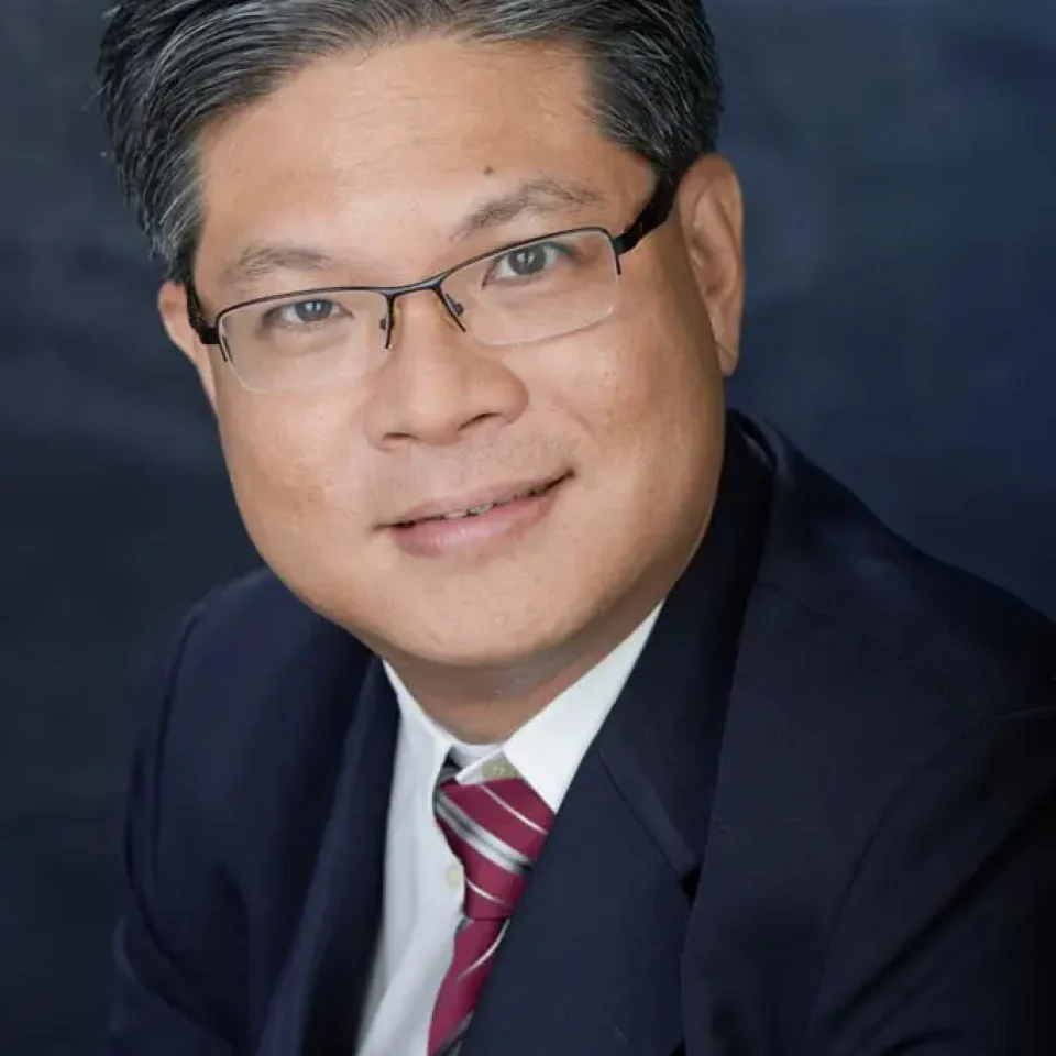 Corporate portrait of a man in glasses and an orange tie against a blue background — singapore C-suite portrait photography, singapore CEO corporate photographer
