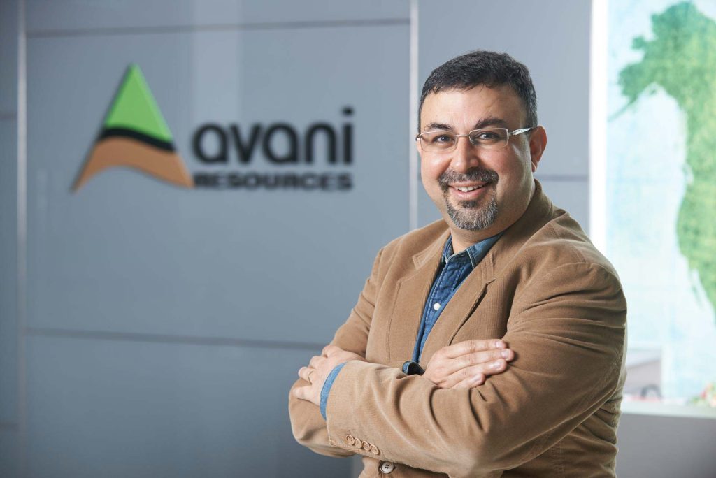 Rajesh Johar, Director of Avani Resources, seated beside the company logo on the office wall