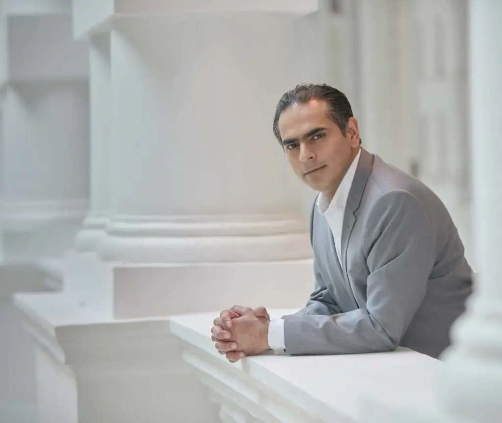 Gaurav Kripalani seated at a table in a high-key setting at Victoria Theatre — environmental portrait photographer singapore, on location corporate portrait singapore