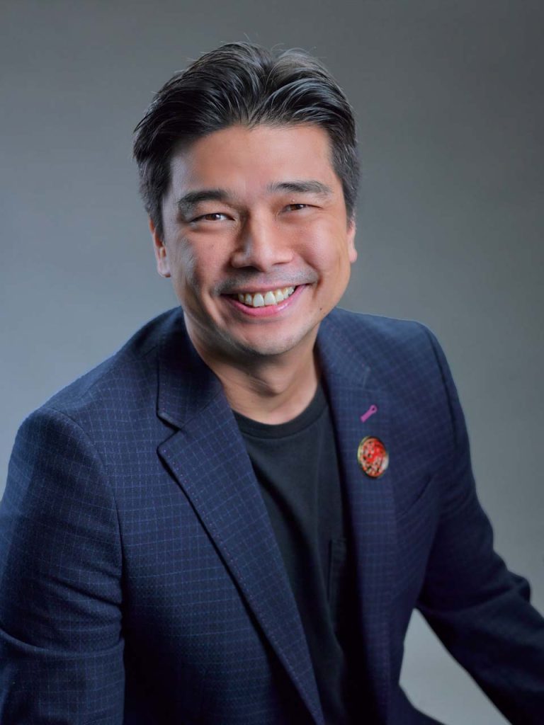 Corporate headshot of Jason Monteiro of Warner Bros. Discovery on a blue background — studio portrait photographer singapore, corporate headshot singapore