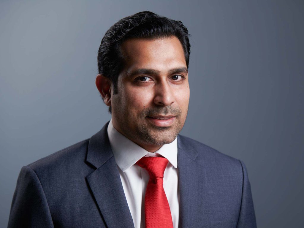 Professional executive headshot of a business executive in a dark suit and red tie against a soft grey background — singapore C-suite portrait photography