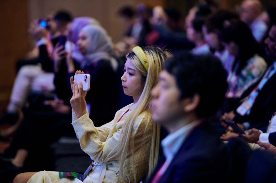 Delegate photographing the stage on a phone at the IAPP Asia Privacy Forum 2024 — singapore corporate events photographer, professional corporate events photography singapore