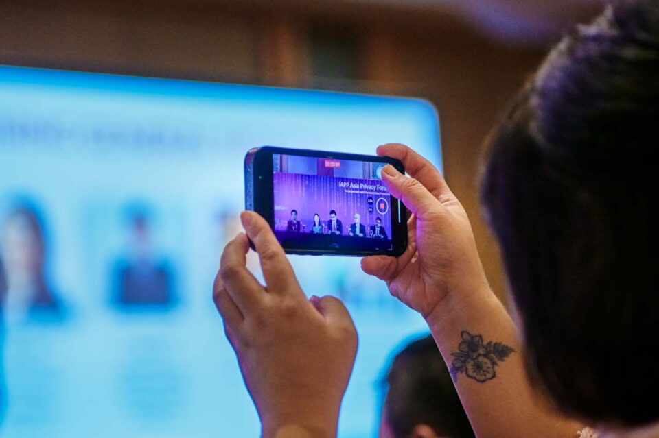 Delegate holding up a phone to photograph a session at the IAPP Asia Privacy Forum 2024 — singapore corporate events photographer, professional corporate events photography singapore