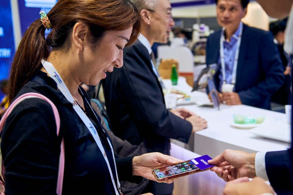 Delegate checking her phone at the Advario stand during Singapore Maritime Week — singapore corporate events photographer, professional corporate events photography singapore