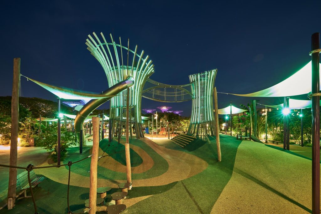 Kompan playground at Gardens by the Bay lit at night, canopy structures glowing green against a blue sky — singapore commercial photographer