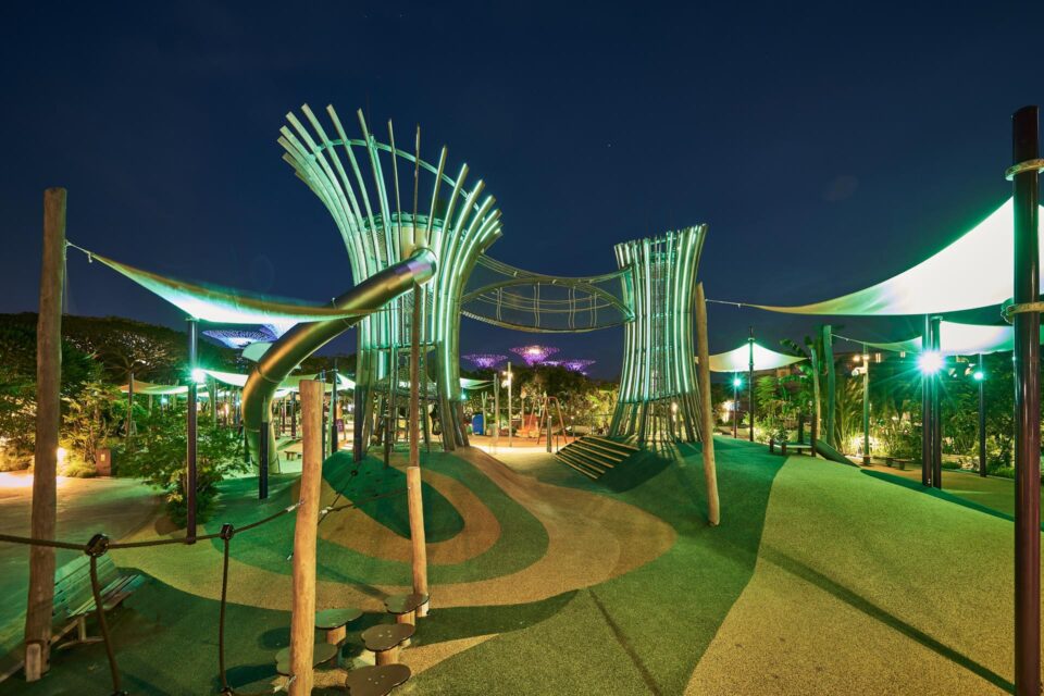 Kompan playground at Gardens by the Bay lit at night, canopy structures glowing green against a blue sky — singapore commercial photographer