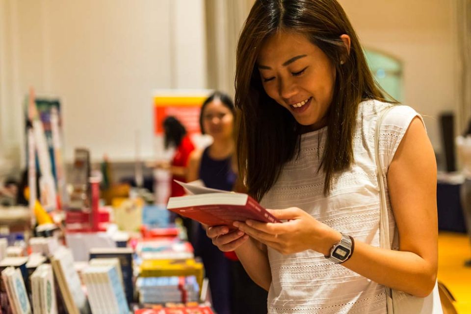 Visitor reading at a brightly lit bookstall during Textures 2018 — singapore corporate events photographer, professional corporate events photography singapore