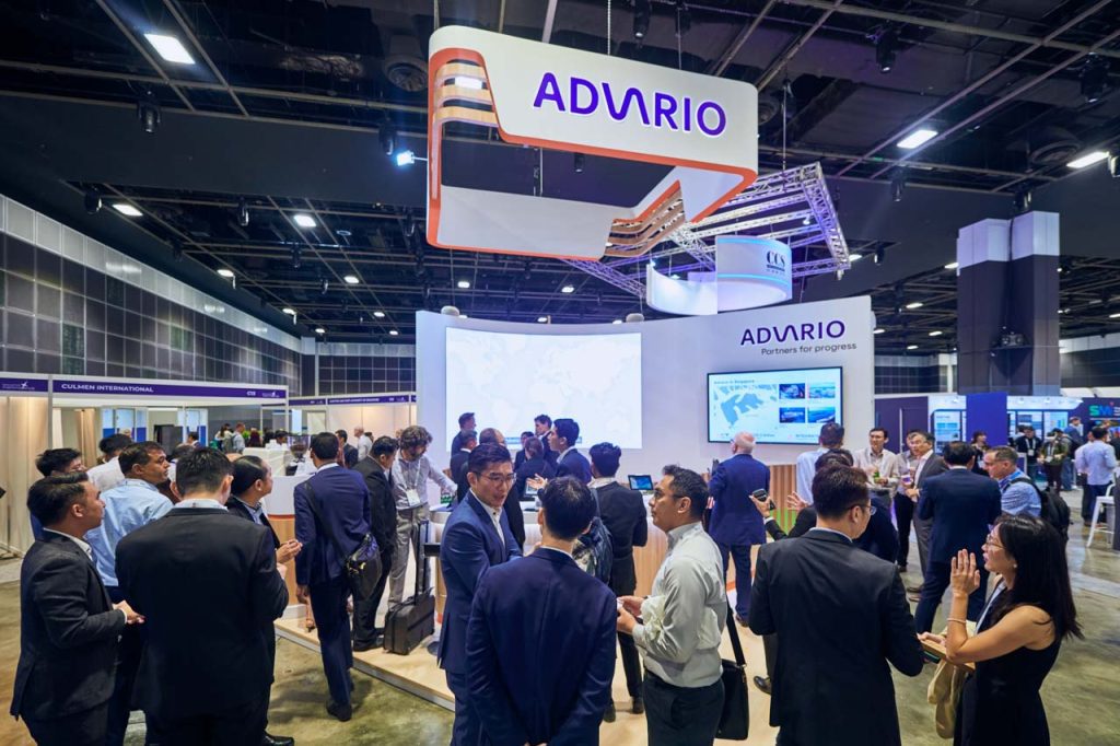 Delegates crossing the exhibition floor past the Advario stand at Singapore Maritime Week 2024