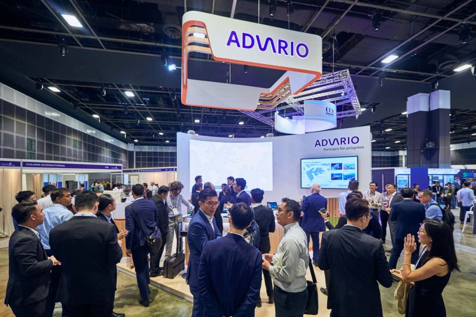 Delegates crossing the exhibition floor past the Advario stand at Singapore Maritime Week 2024 — singapore corporate events photographer