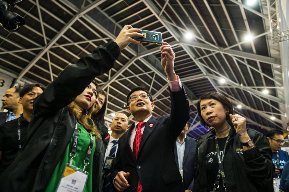 Guests with hands raised in celebration beneath a steel and glass canopy at a Singapore corporate event — singapore commercial photographer