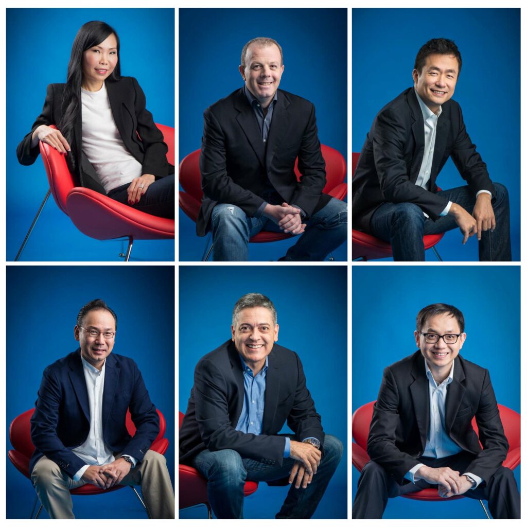 Six matched studio portraits of executives on a blue backdrop with red chairs, arranged as one leadership set — singapore C-suite portrait photography