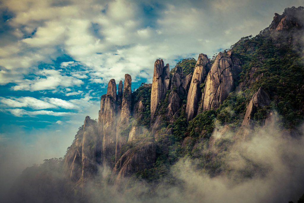 Granite peaks rising out of cloud and mist on a forested mountainside at Sanqingshan, China — professional travel landscape photography by a Singapore photographer