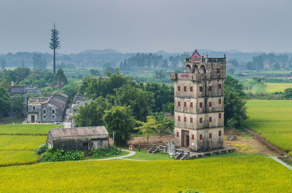A watchtower with red shutters standing in ripening rice fields beside village houses, Guangzhou, China — professional travel landscape photography by a Singapore photographer